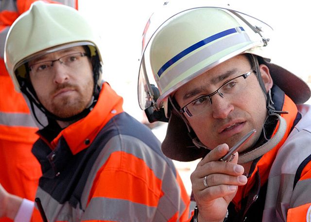 Zwei Einsatzkräfte mit Helm und Warnkleidung besprechen sich im Einsatz