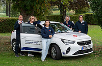 Team der Leitung der mobilen Pflege des DRK Schwalm-Eder vor einem Dienstauto mit DRK Logo.