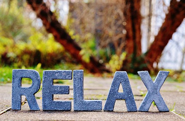 Schriftzug „RELAX" aus blauen Buchstaben vor herbstlichem Hintergrund