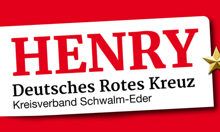 Ein weißes, leicht schräg gestelltes Schild auf einem leuchtend roten Hintergrund. Auf dem Schild steht in großen, roten Buchstaben "HENRY". Darunter ist in schwarzer Schrift "Deutsches Rotes Kreuz" und in einer noch kleineren Zeile darunter "Kreisverband Schwalm-Eder" zu lesen. Am rechten Rand des weißen Schildes ist ein kleiner, dreidimensionaler goldener Stern angebracht.