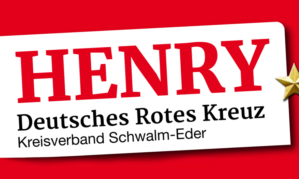 2026-07-09 - Henry Ein weißes, leicht schräg gestelltes Schild auf einem leuchtend roten Hintergrund. Auf dem Schild steht in großen, roten Buchstaben "HENRY". Darunter ist in schwarzer Schrift "Deutsches Rotes Kreuz" und in einer noch kleineren Zeile darunter "Kreisverband Schwalm-Eder" zu lesen. Am rechten Rand des weißen Schildes ist ein kleiner, dreidimensionaler goldener Stern angebracht.