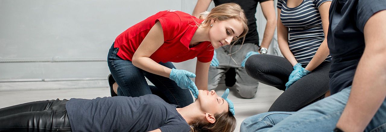 Erste-Hilfe-Training: Eine Teilnehmerin überprüft die Atmung einer am Boden liegenden Person