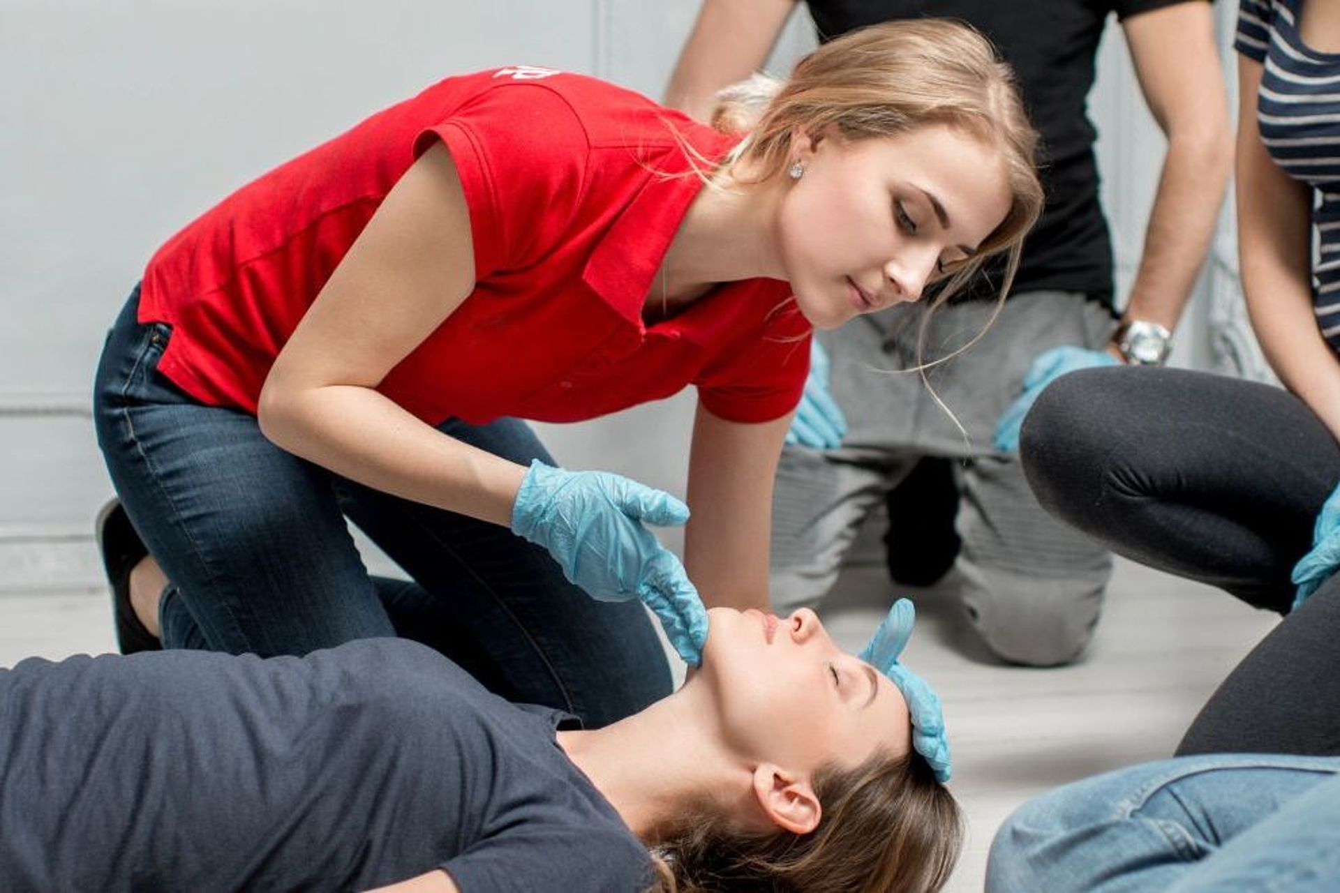 Erste-Hilfe-Training: Eine Teilnehmerin überprüft die Atmung einer am Boden liegenden Person