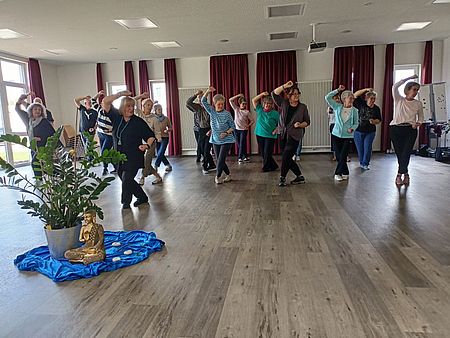 Ein Gruppe in einem Kursraum während einer Qigong-Übung